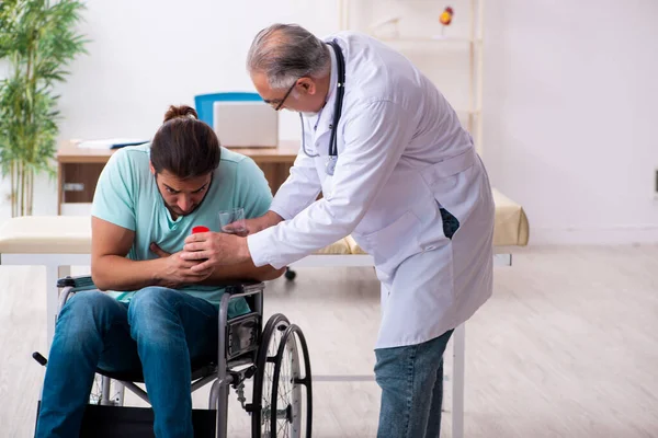 Médico experimentado y joven paciente masculino en silla de ruedas — Foto de Stock