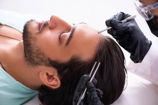 Young man visiting female beautician in hair transplantation con — Stock Photo, Image