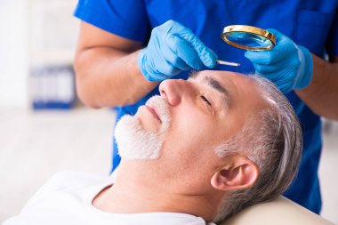 Yaşlı adam saç nakli için genç erkek doktoru ziyaret ediyor.