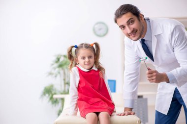 Küçük kız genç erkek doktoru ziyaret ediyor.