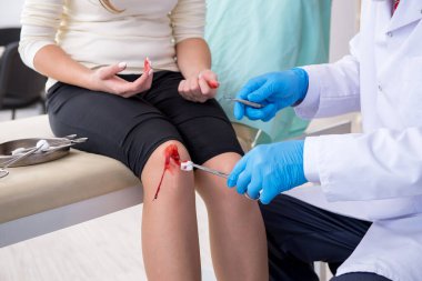 Erkek doktoru ziyaret eden bacağı yaralı bir kadın.