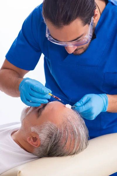 Old man visiting young male doctor in hair transplantation conce — Stock Photo, Image