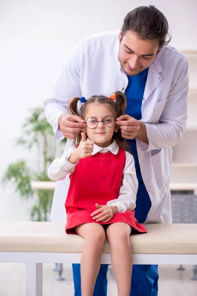 Piccola ragazza in visita giovane medico maschio oculista — Foto Stock