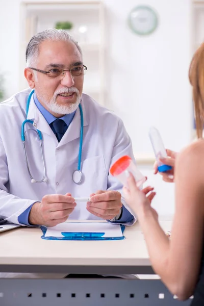 Jeune femme visitant vieux médecin masculin — Photo