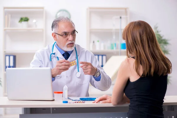 Jovem mulher visitando velho médico masculino — Fotografia de Stock