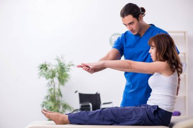 Yaralı kadın genç erkek doktor osteopat 'ı ziyaret ediyor.