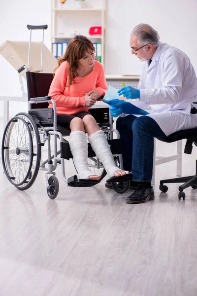 Joven pierna lesionada mujer visitando viejo médico traumatólogo — Foto de Stock
