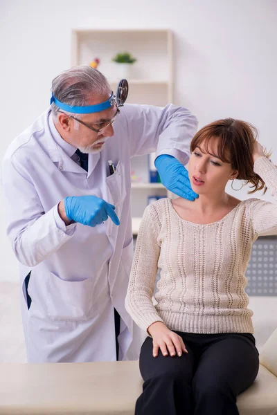 Giovane donna in visita vecchio medico maschio otorinolaringoiatra — Foto Stock