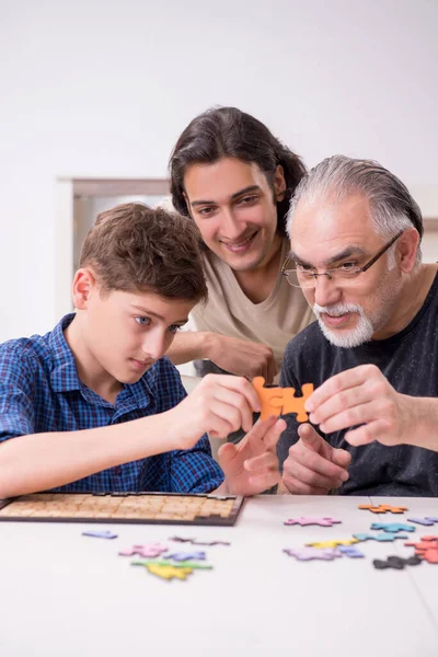 Tre generationer av familj spelar pusselspel — Stockfoto