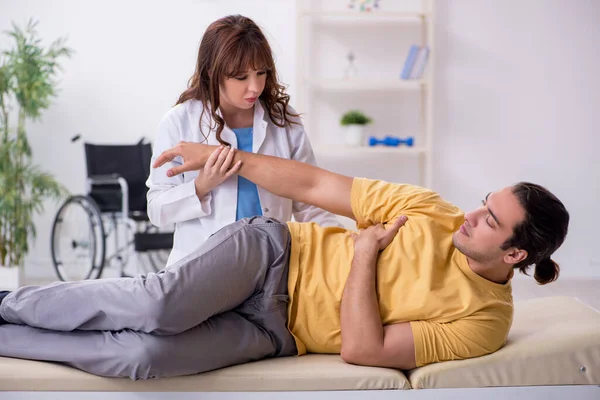 Gewonde man op bezoek bij jonge vrouwelijke arts osteopaat — Stockfoto