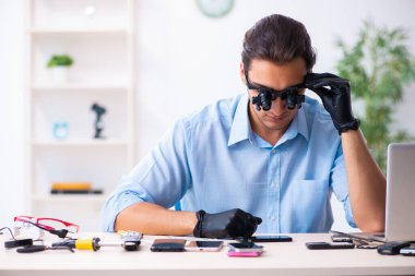 Cep telefonunu tamir eden genç bir teknisyen.