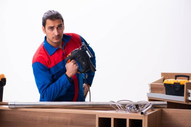 Genç yakışıklı erkek marangoz içeride çalışıyor.