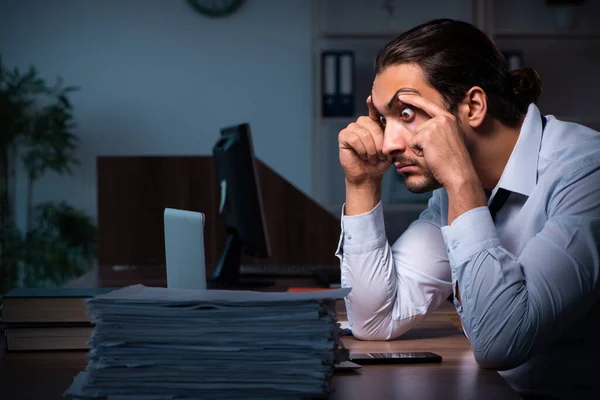 Jonge mannelijke werknemer die 's nachts op kantoor werkt — Stockfoto