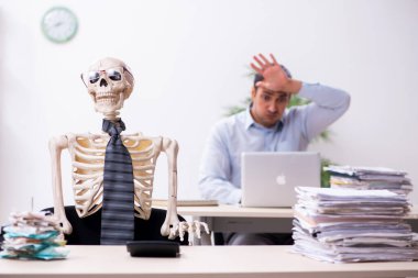 Genç erkek çalışan ve iskelet ofiste.