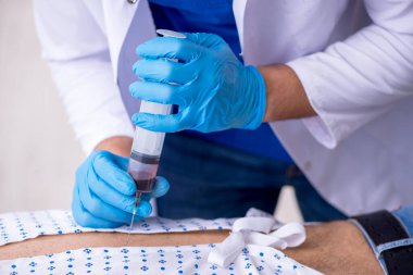 Yaşlı adam genç erkek stajyer doktoru ziyaret ediyor.