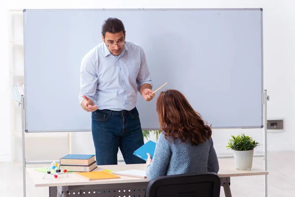 Young female student and male teacher in the classroom — Stock Photo, Image