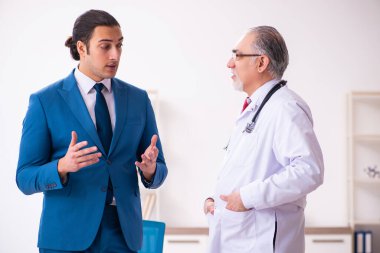 Genç işadamı yaşlı doktorla görüşüyor.