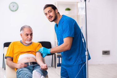 Yaşlı adam genç erkek doktoru ziyaret ediyor.