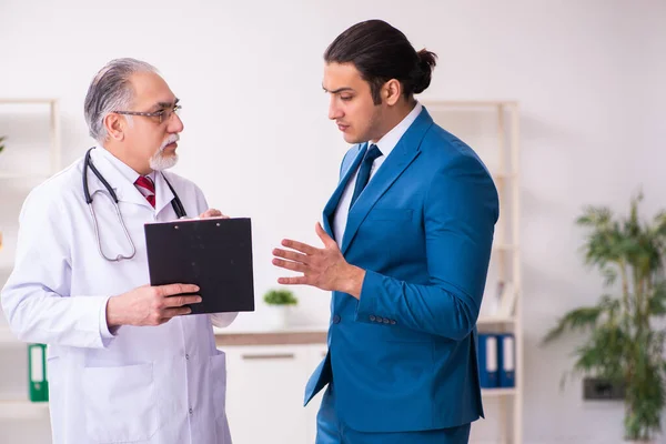 Jeune homme d'affaires rencontre avec un vieux médecin — Photo