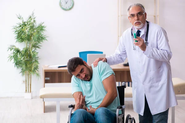 Ervaren arts en jonge mannelijke patiënt in rolstoel — Stockfoto