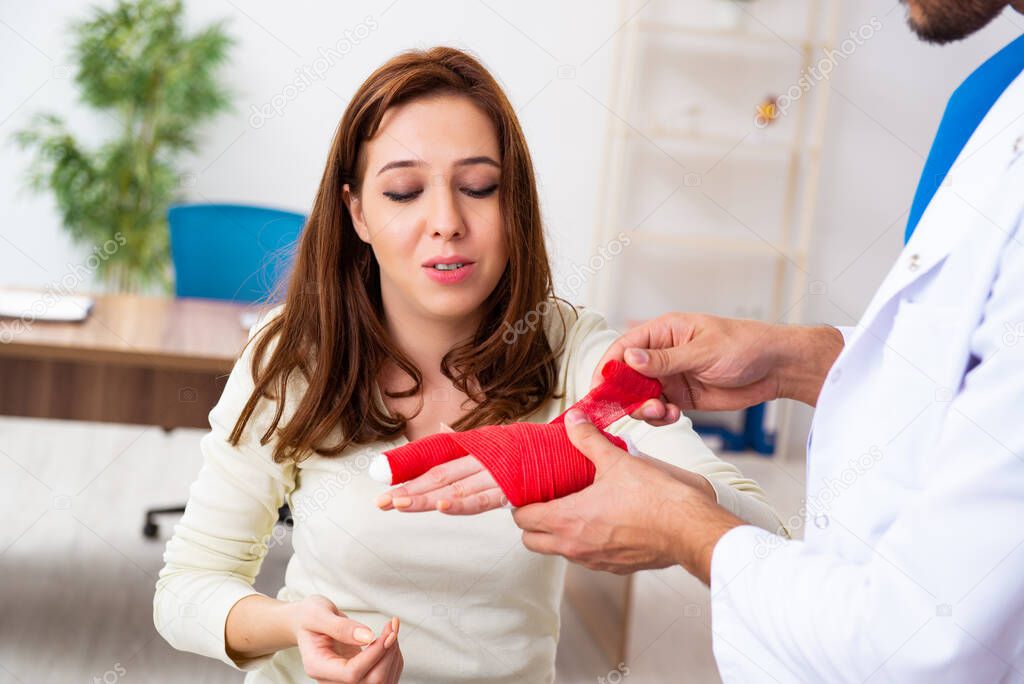 Young hand injured woman visiting male doctor traumatologist