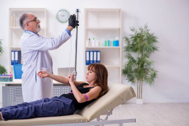 Genç kadın yaşlı erkek doktoru ziyaret ediyor.