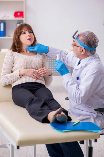 Jovem mulher visitando velho médico otorrinolaringologista masculino — Fotografia de Stock