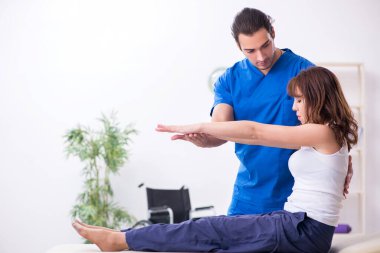 Yaralı kadın genç erkek doktor osteopat 'ı ziyaret ediyor.