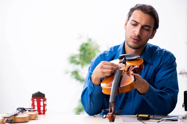 Young male repairman repairing violin