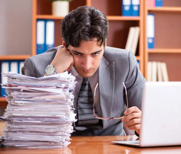 Jonge knappe zakenman ongelukkig met buitensporig werk — Stockfoto