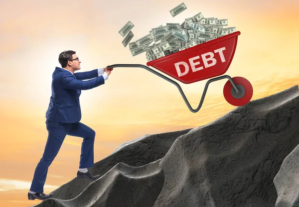 Empresario empujando carretilla cuesta arriba en concepto de préstamo de deuda —  Fotos de Stock