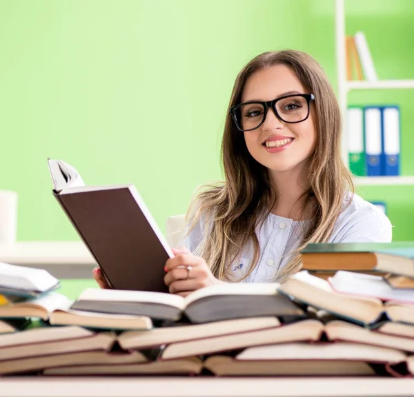 Jonge vrouwelijke student bereidt zich voor op examens met veel boeken — Stockfoto