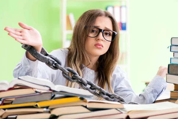 Jonge vrouwelijke student geketend aan het bureau en voor te bereiden op examens — Stockfoto