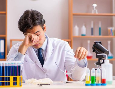 Genç yakışıklı biyokimyacı laboratuvarda çalışıyor.