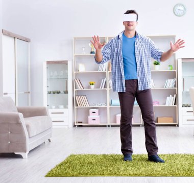 Evde sanal gerçeklik gözlüklü bir adam oynuyor.