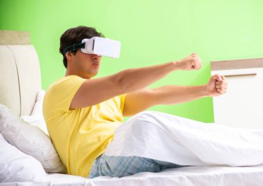 Yatak odasında sanal gözlüklü genç adam.