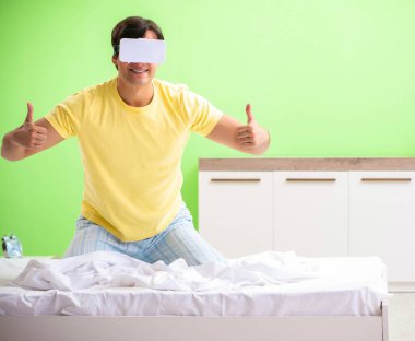 Yatak odasında sanal gözlüklü genç adam.