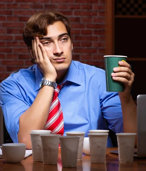 Junger Mitarbeiter trinkt Kaffee bei Nachtschicht — Stockfoto