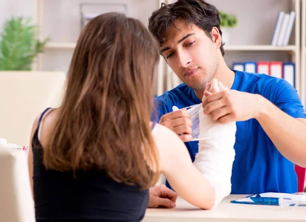 Junge Frau mit bandagiertem Arm besucht männlichen Arzt — Stockfoto