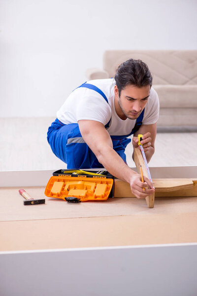 Young male contractor installing furniture at home