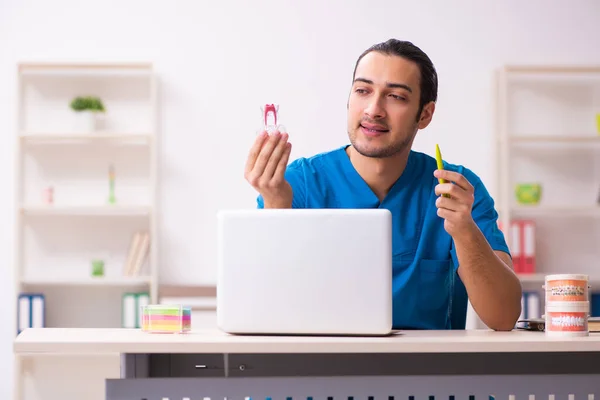 Jovem dentista do sexo masculino que trabalha na clínica — Fotografia de Stock