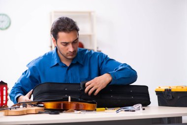 Kemanı tamir eden genç bir erkek tamirci