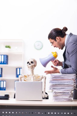 Genç erkek çalışan ve iskelet ofiste.