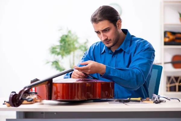 Joven reparador masculino reparando violonchelo —  Fotos de Stock