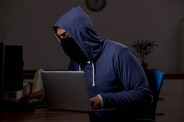 Male hacker hacking security firewall late in office