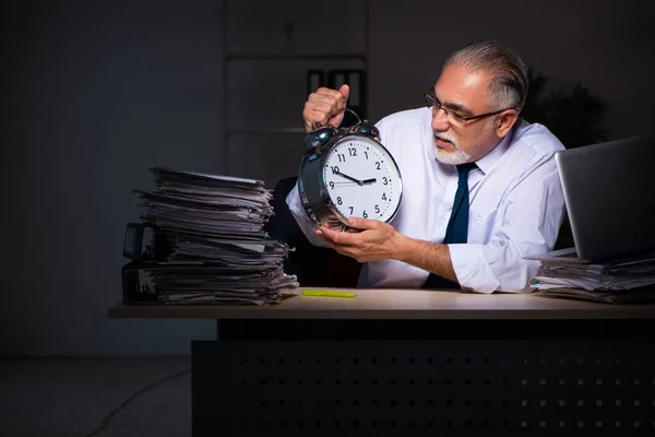 Oude mannelijke werknemer die laat op de werkplek werkt — Stockfoto