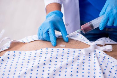 Yaşlı adam genç erkek stajyer doktoru ziyaret ediyor.