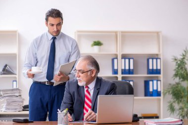 Eski patron ve genç erkek çalışan ofiste.