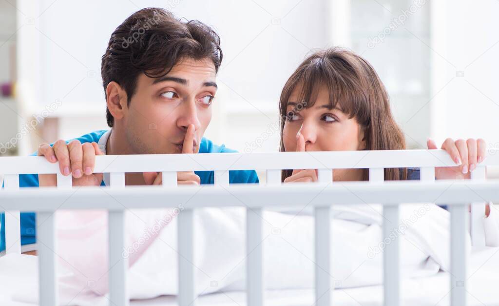 Happy young family at baby bed cot