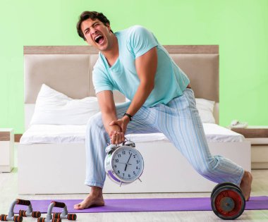 Pijamalı genç adam sabah egzersizi yapıyor.